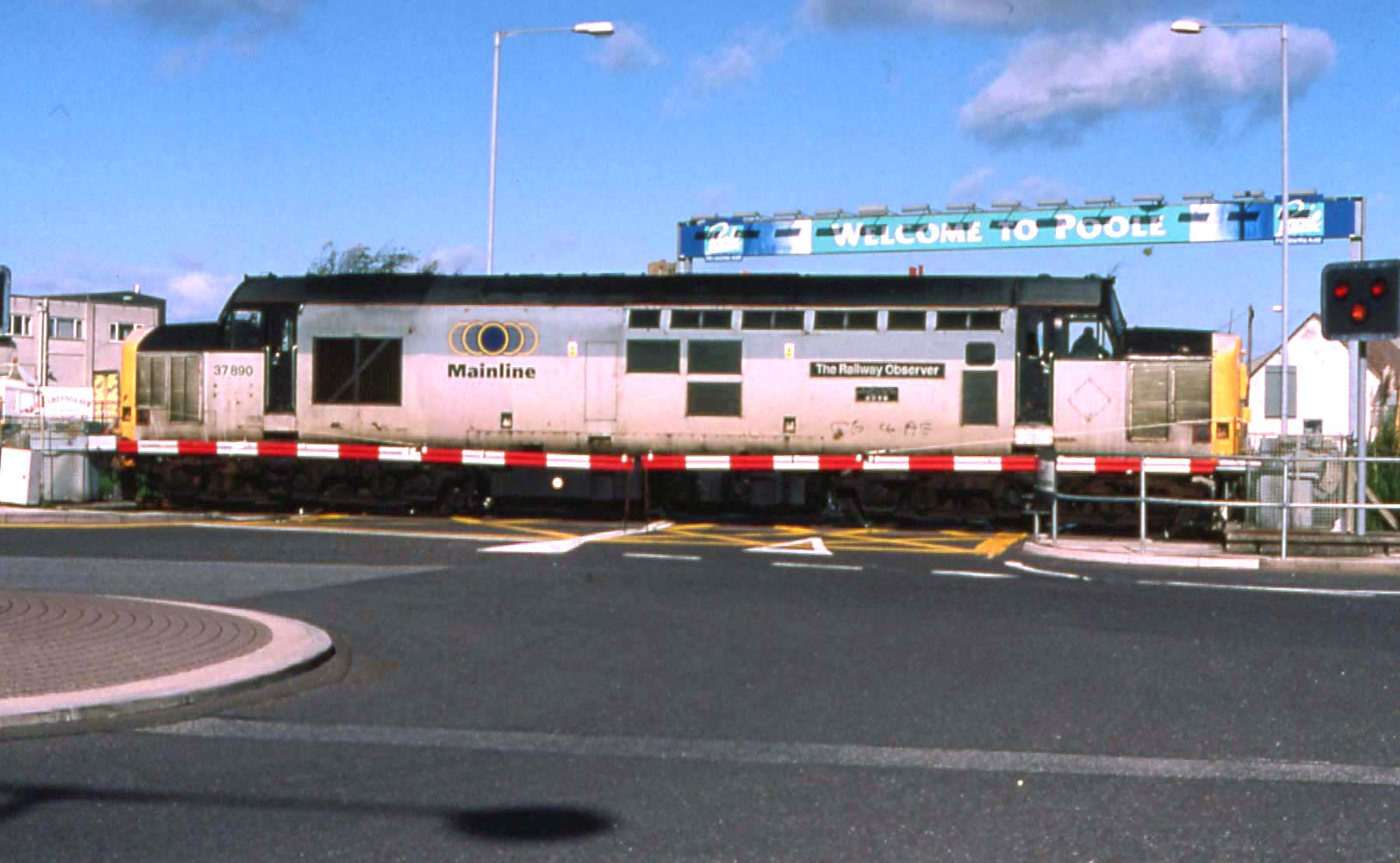 37890 running round on Hamworthy branch, 17th October 1998. The level crossing is the main road entrance for the cross channel ferry port, hence the “Welcome to Poole” sign in the background. Martyn Thresh