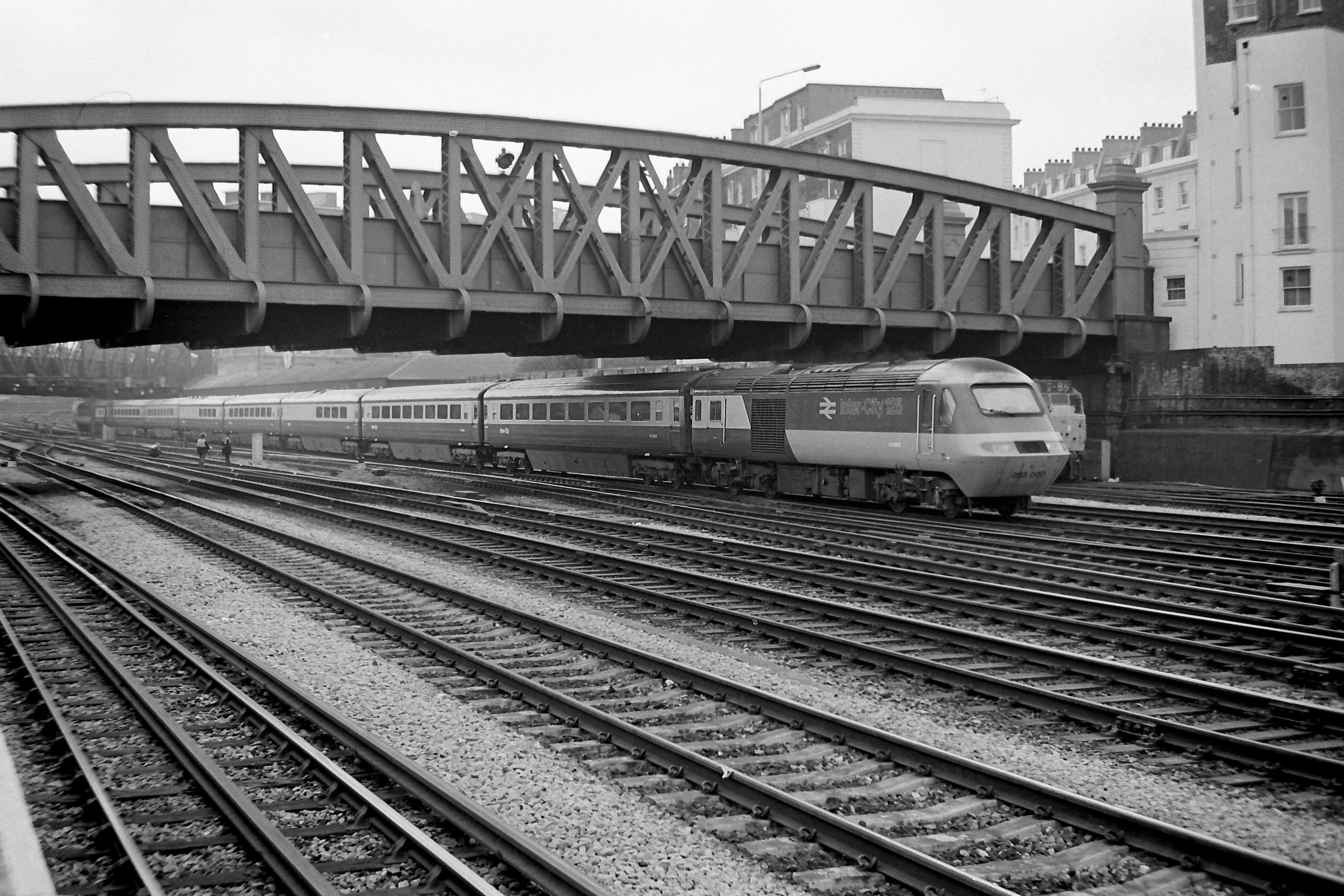 In the initial IC 125 livery as introduced on the Western Region the power car is photographed leaving Paddington on a service heading westwards on 21st April 1977. The picture is taken from Royal Oak underground station platforms which now no longer exist. Note set number 253 007 low down on the ‘nose’ Bob Green