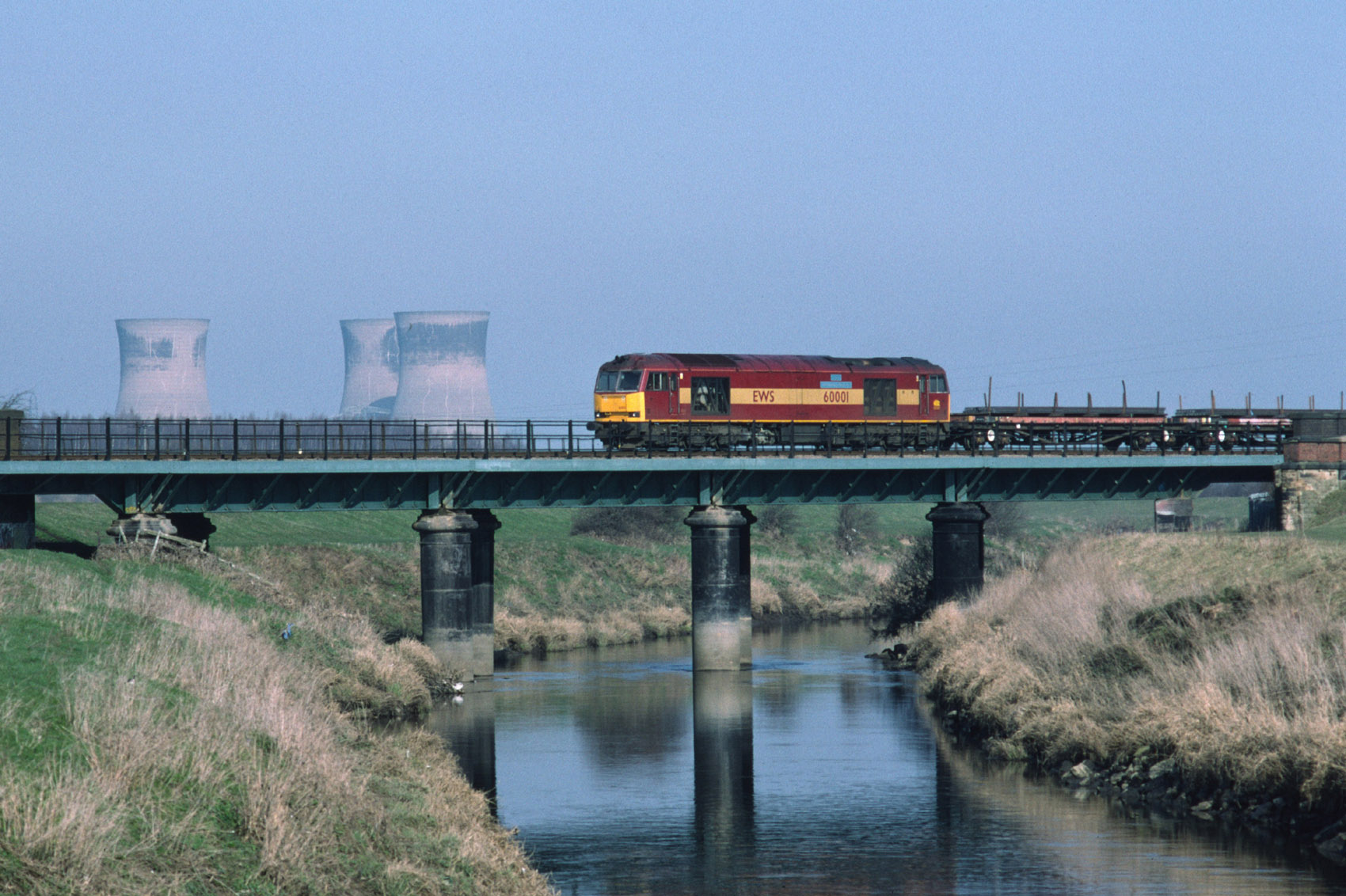 60001 (The Railway Observer) heading west over the River Don at Long Sandall (nr Kirk Sandall station) with a loaded steel train (6J48) from Scunthorpe to Aldwarke on 02/03/04. The cooling towers of the disused Thorpe Marsh power station are in the background.